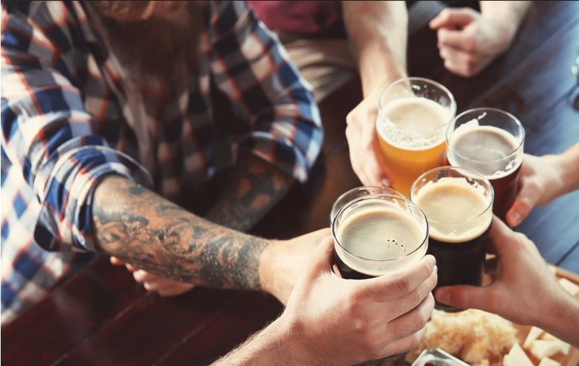 A group of friends clinking glasses of beer in a toast, showcasing various brews in vibrant shades, creating a lively and welcoming atmosphere.