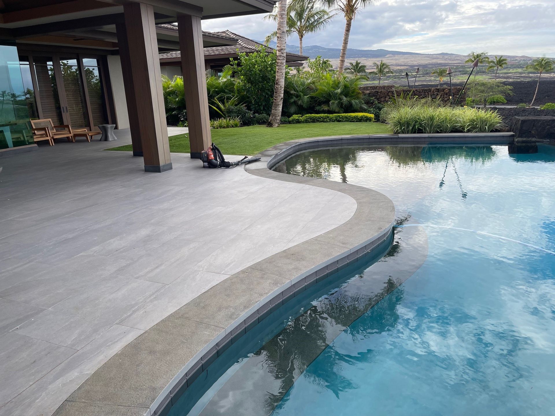 There is a large swimming pool in the backyard of a house