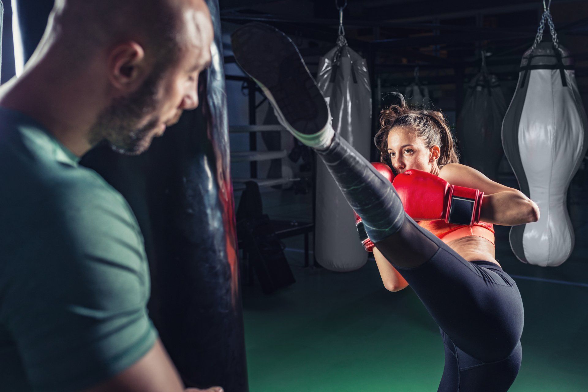 One on one kickboxing training with coach by holding the bag  while trainee is kicking as high s she could