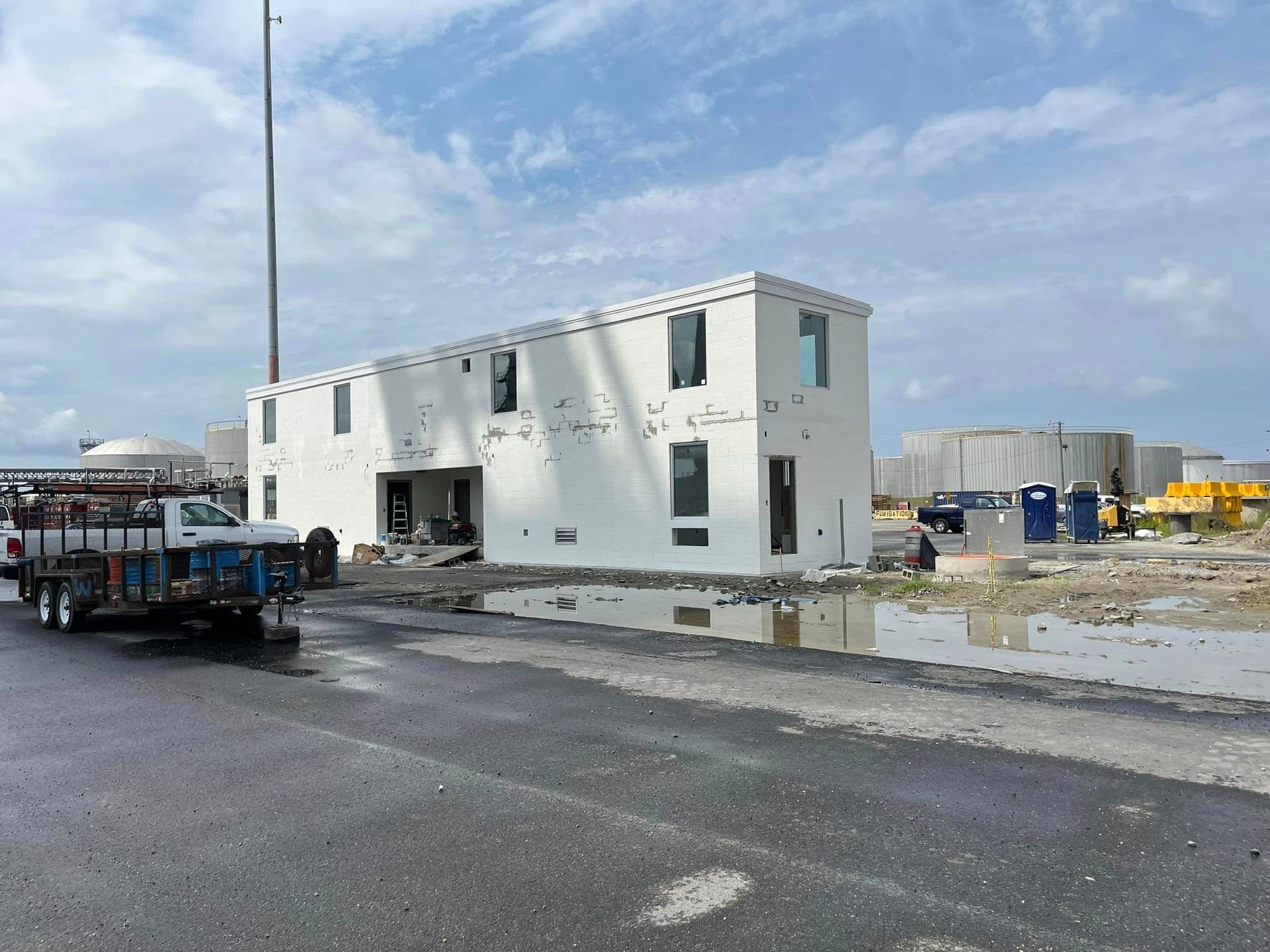 A white truck is parked in front of a building under construction.
