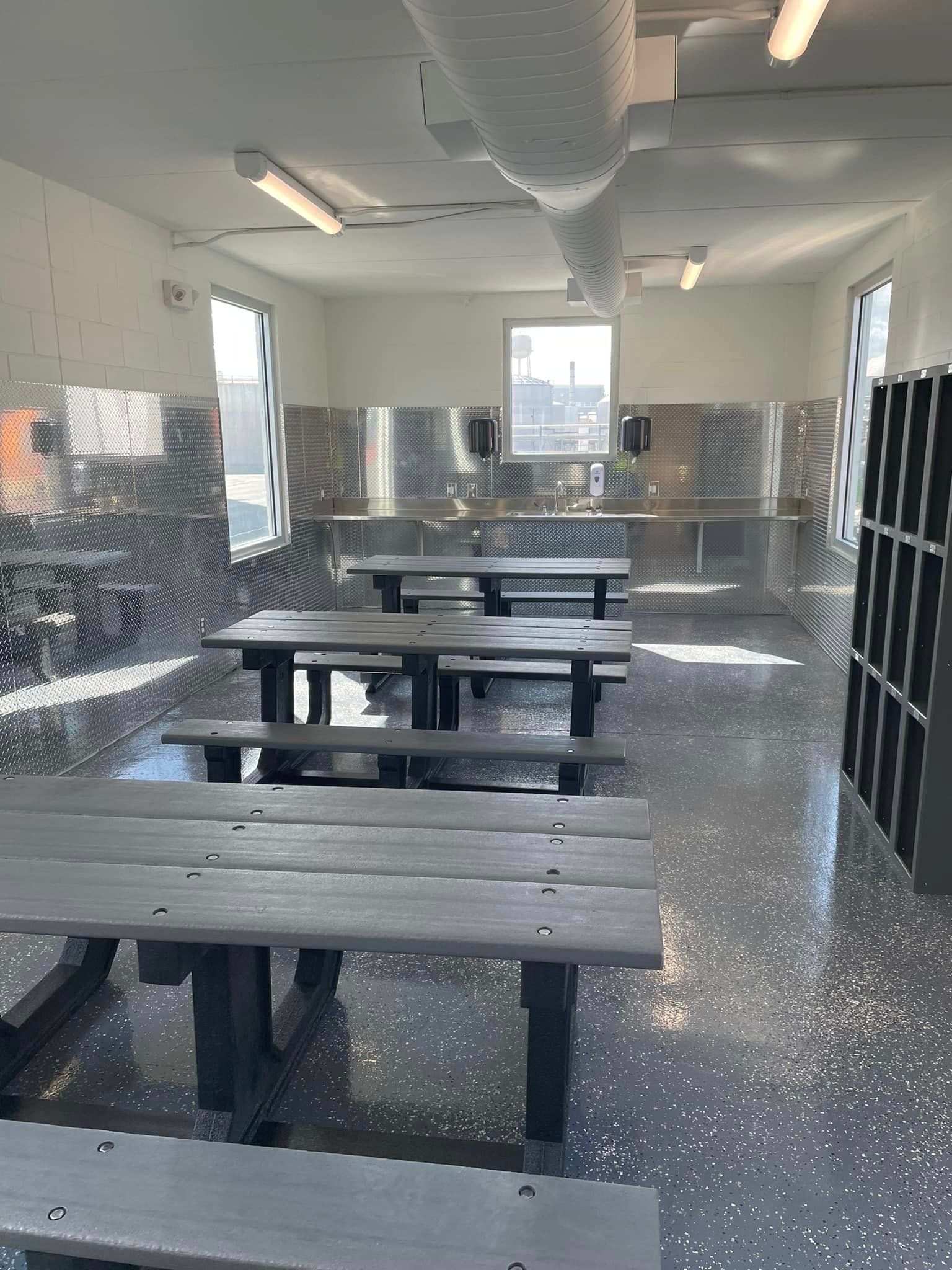 A room with a lot of tables and benches in it.