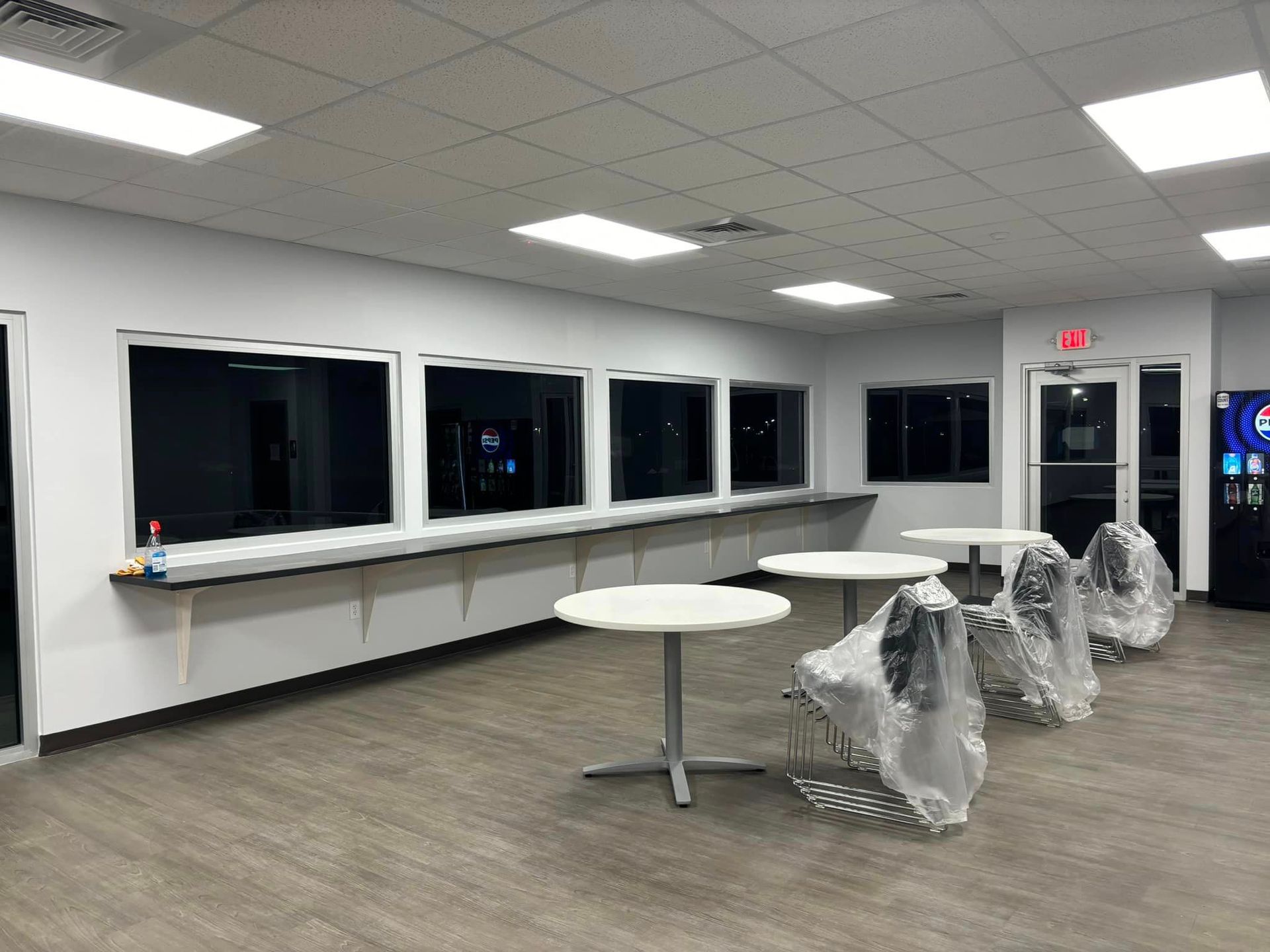 A large room with tables and chairs and a vending machine.