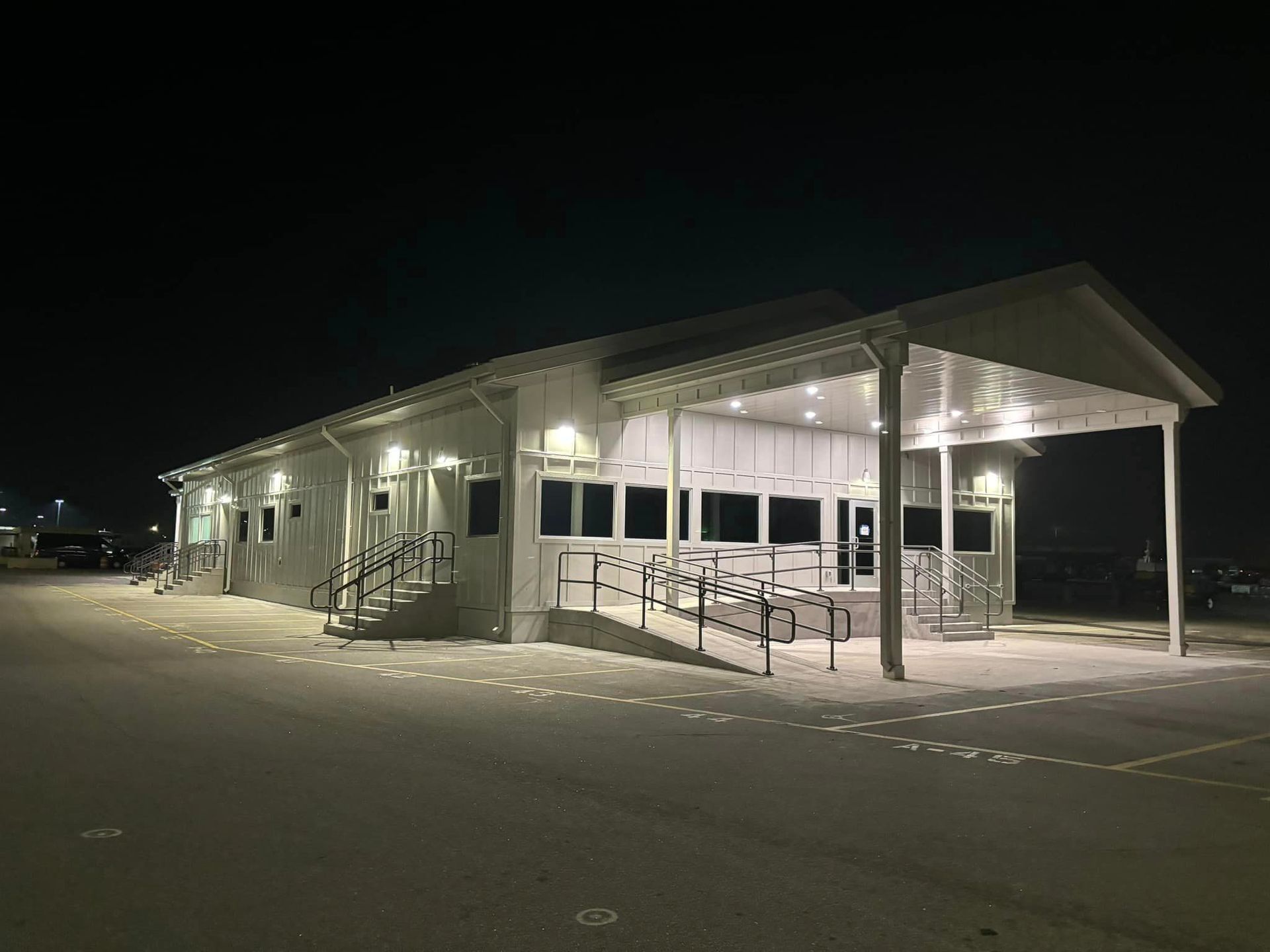 A large white building with a ramp is lit up at night.