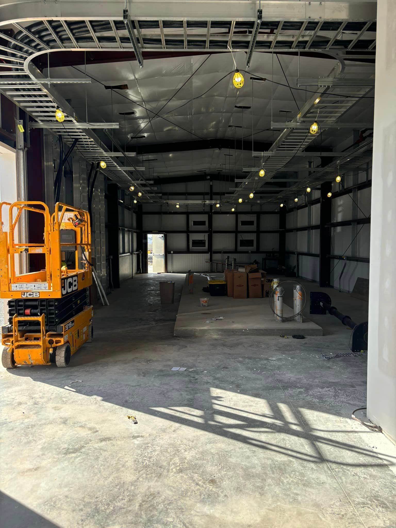 A large empty warehouse with a lift in the middle of it.