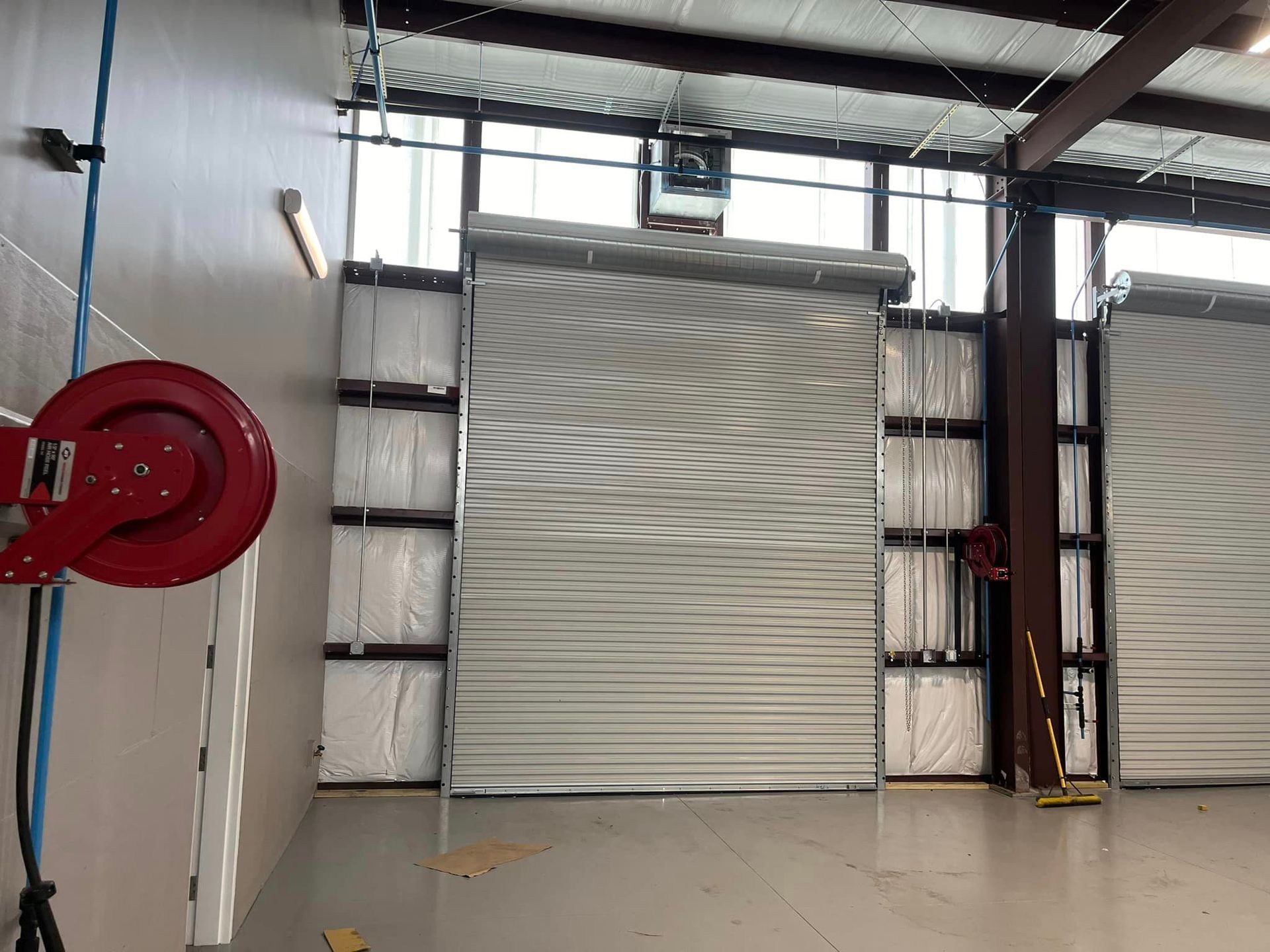 An empty garage with a red hose reel on the wall