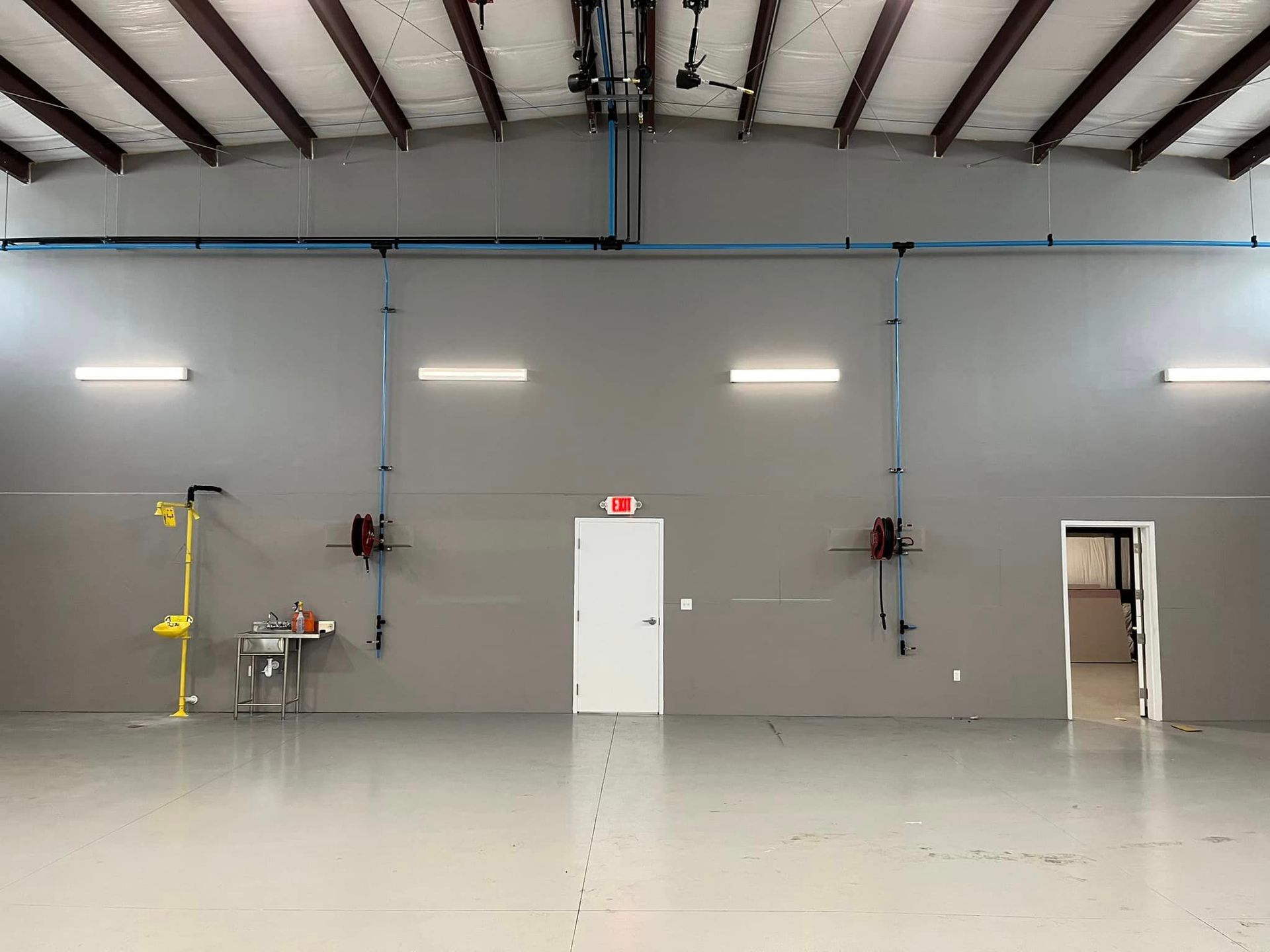 An empty warehouse with a white door and a sink.