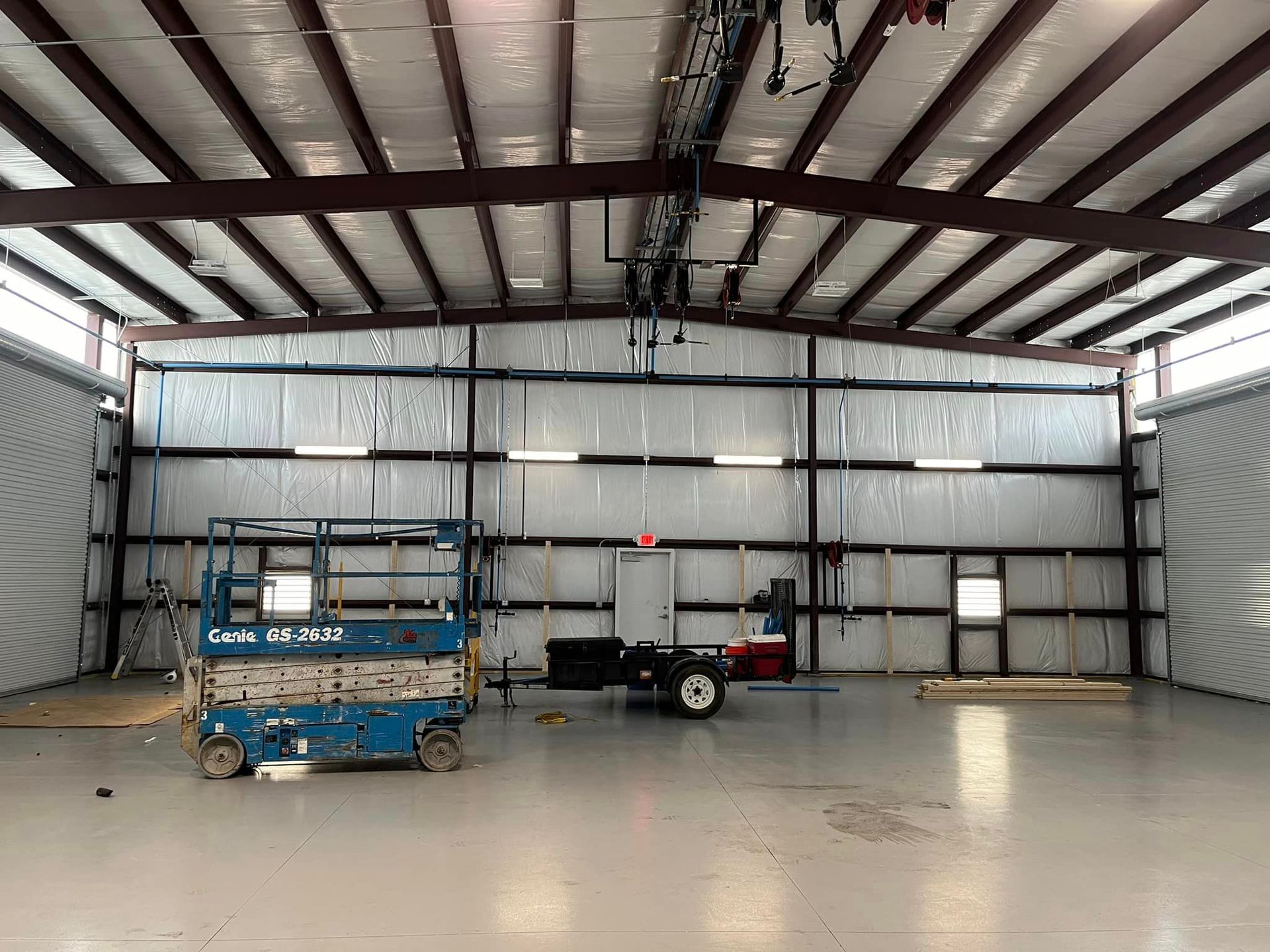 A blue scissor lift is parked inside of a large warehouse.