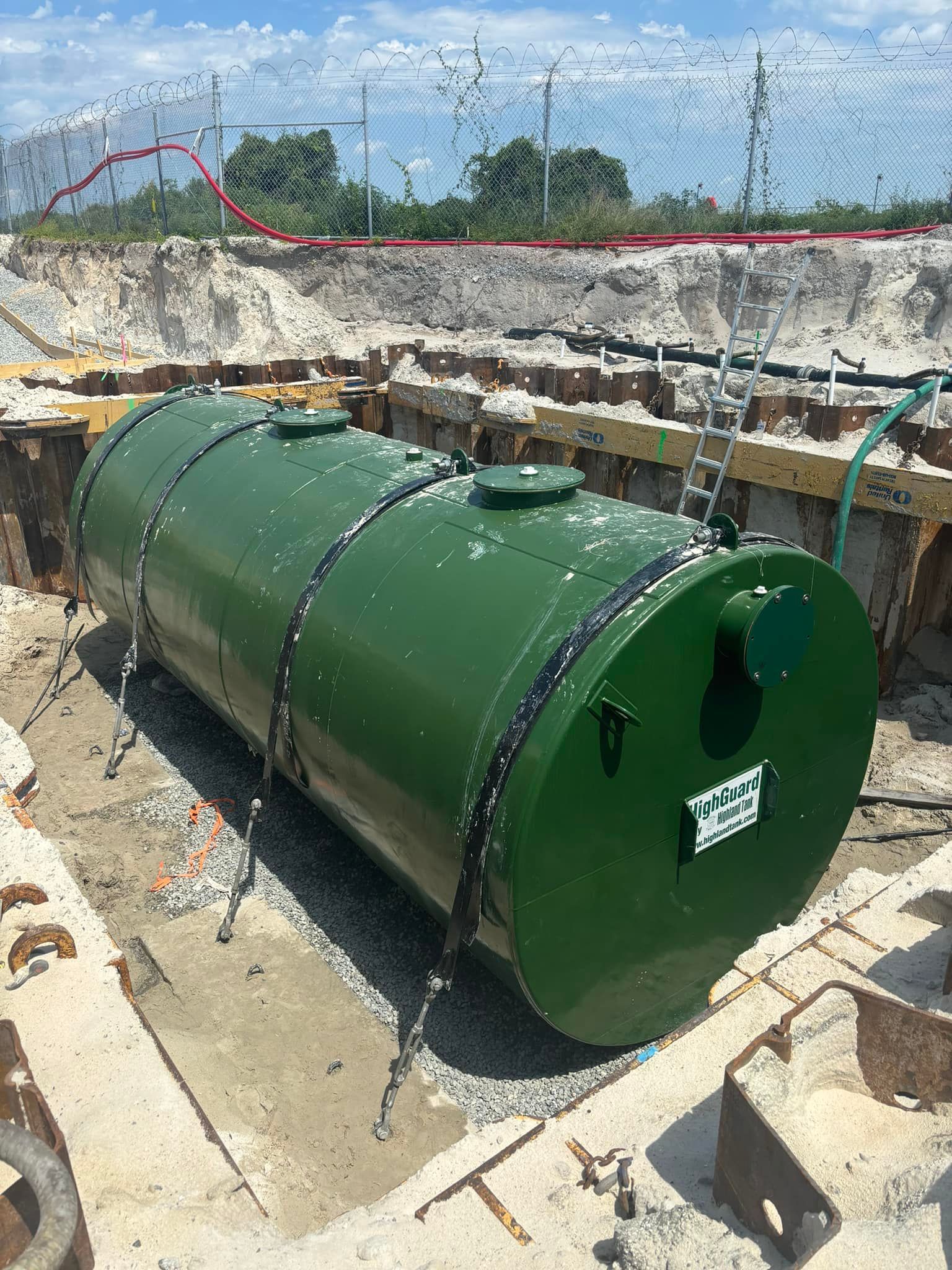 A large green tank is sitting in a hole in the ground.