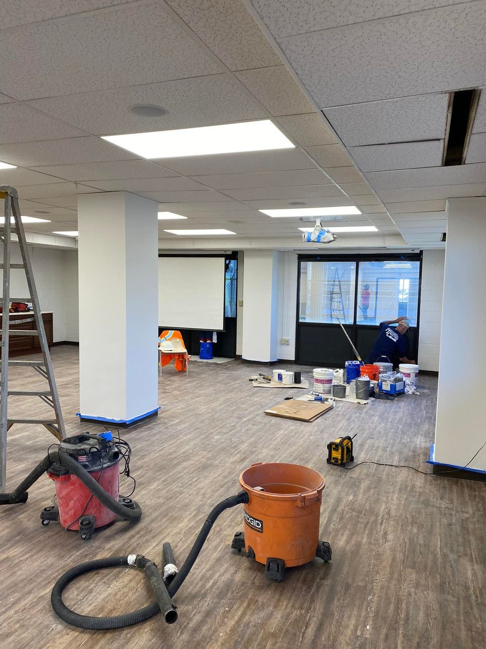 An empty room with a vacuum cleaner and a ladder in it.