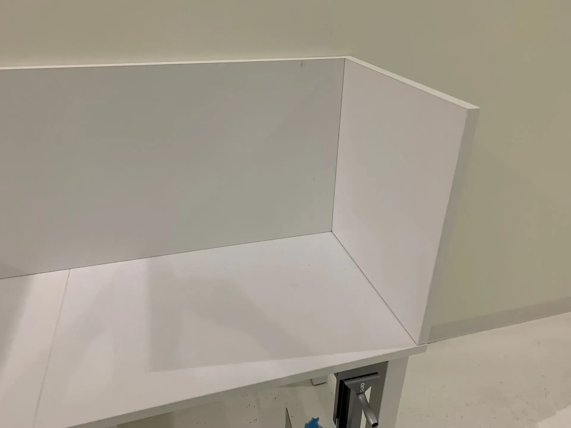 White shelving unit being assembled against a light wall; the unit is open, showing its interior.