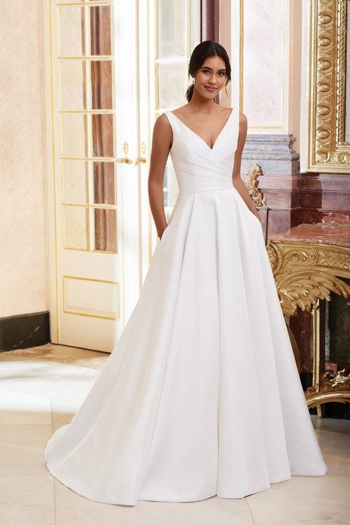 A woman in a white wedding dress is standing in front of a door.