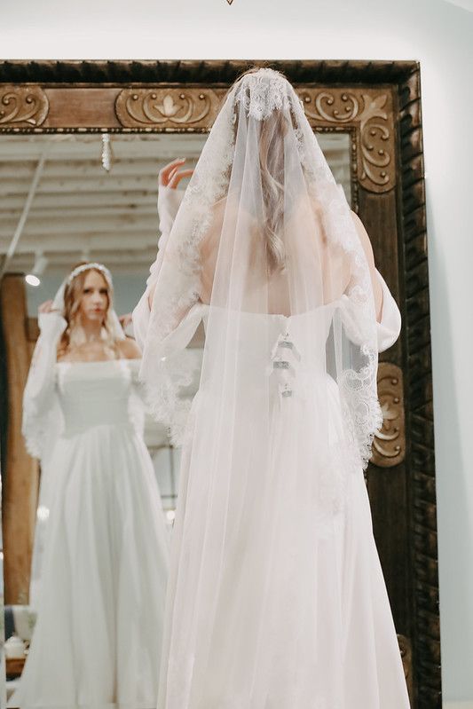 A woman in a white wedding dress is standing on a wooden deck.