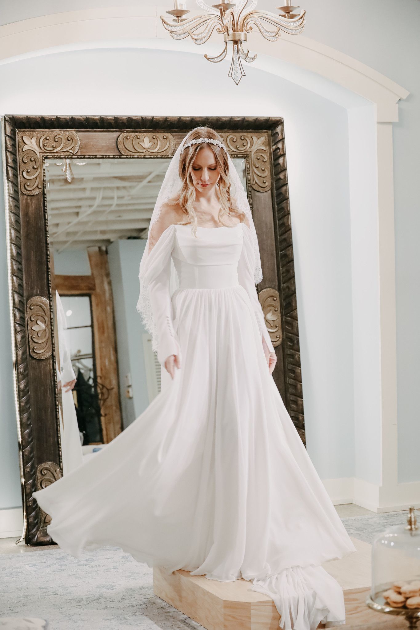 A woman is wearing a white wedding dress and standing in front of a building.