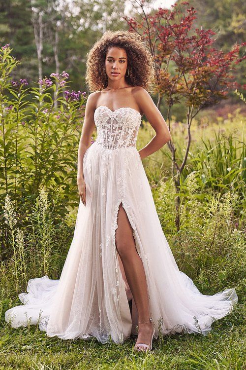 A woman in a wedding dress is standing in a field.