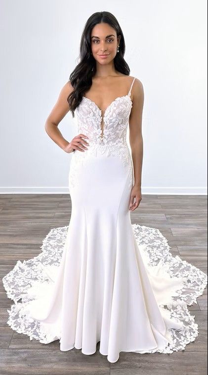Woman in a white lace wedding gown standing against a plain wall with a long train. Argentina — DR2302