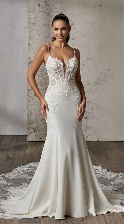 Woman in a white lace mermaid wedding dress standing against a concrete wall. Laguna - DR2610