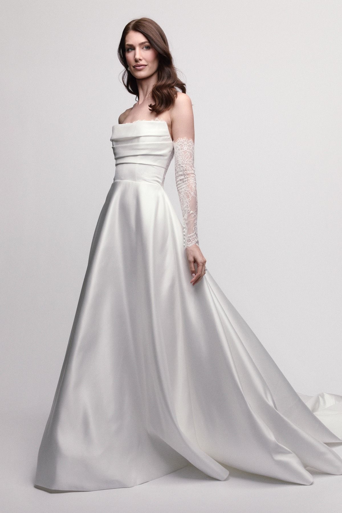 Woman in white off-the-shoulder wedding dress, standing, looking forward, studio setting.