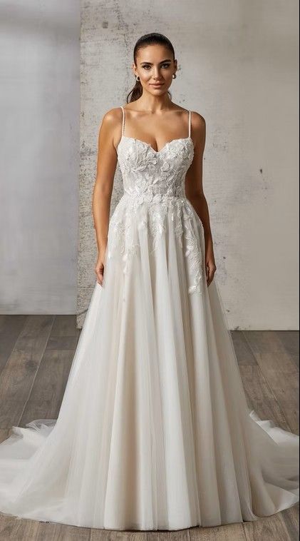 Bride in a white lace wedding gown with a long train, standing against a gray studio backdrop. Matilda - EK1809