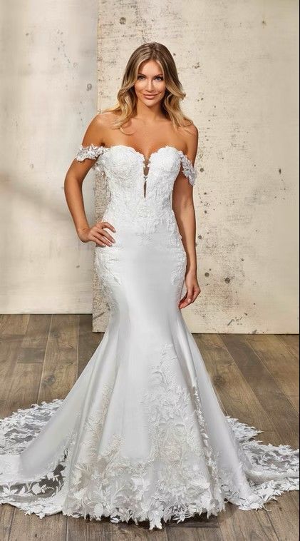 Woman in a white off-shoulder mermaid wedding gown posing against a textured wall. Niza - DR2506