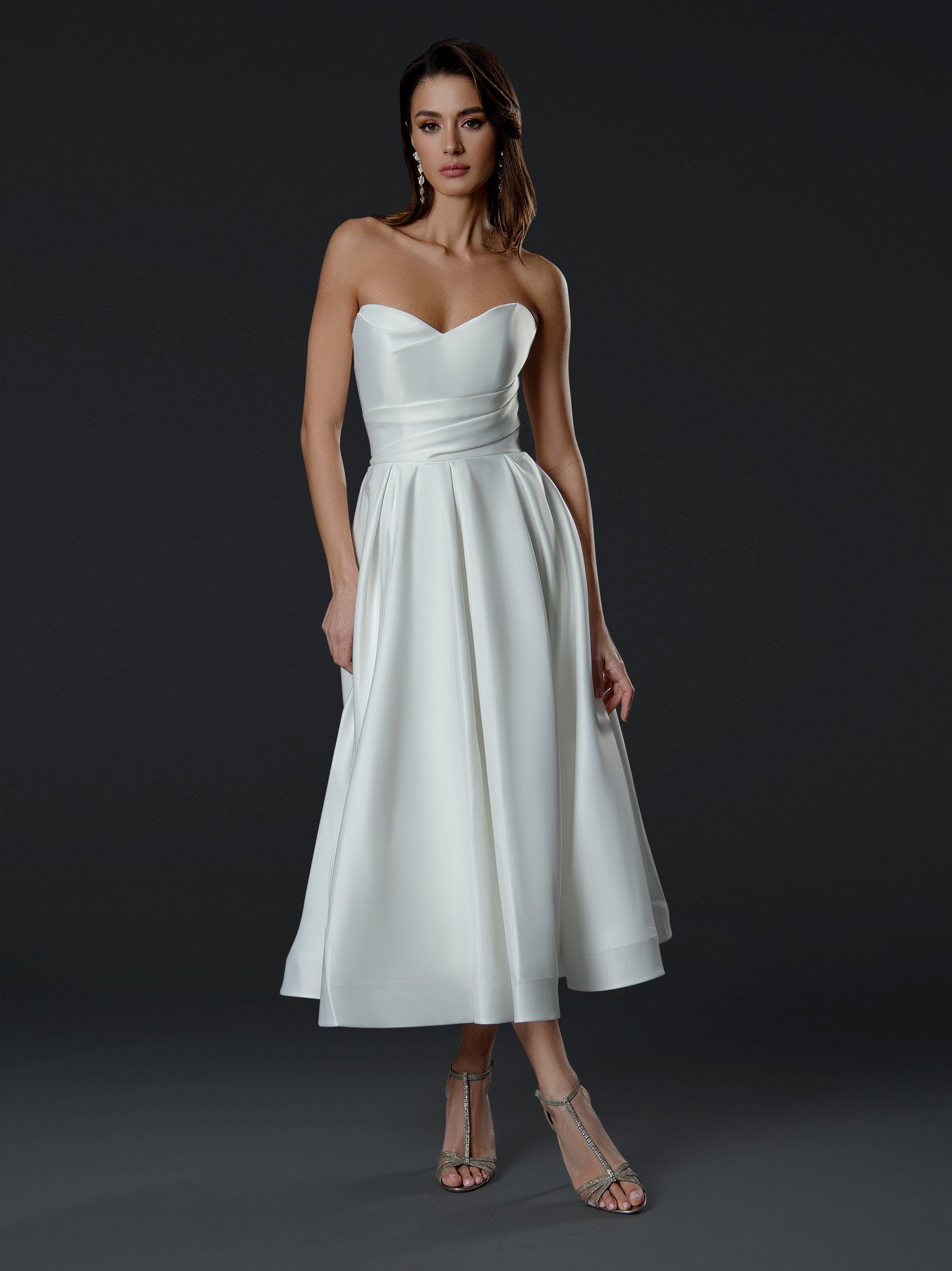 A woman in a white dress is standing in front of a black background