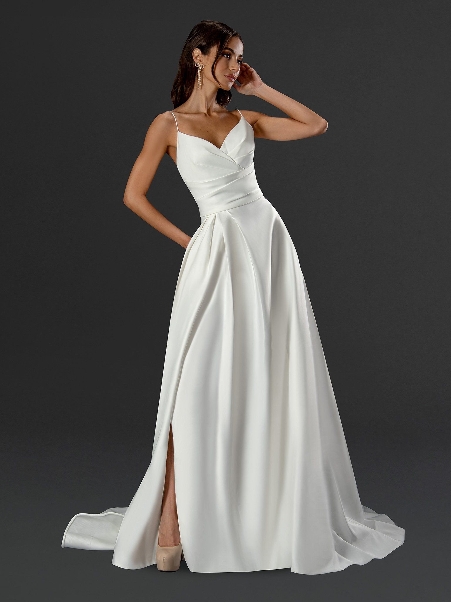 A woman in a white dress is standing in front of a black background