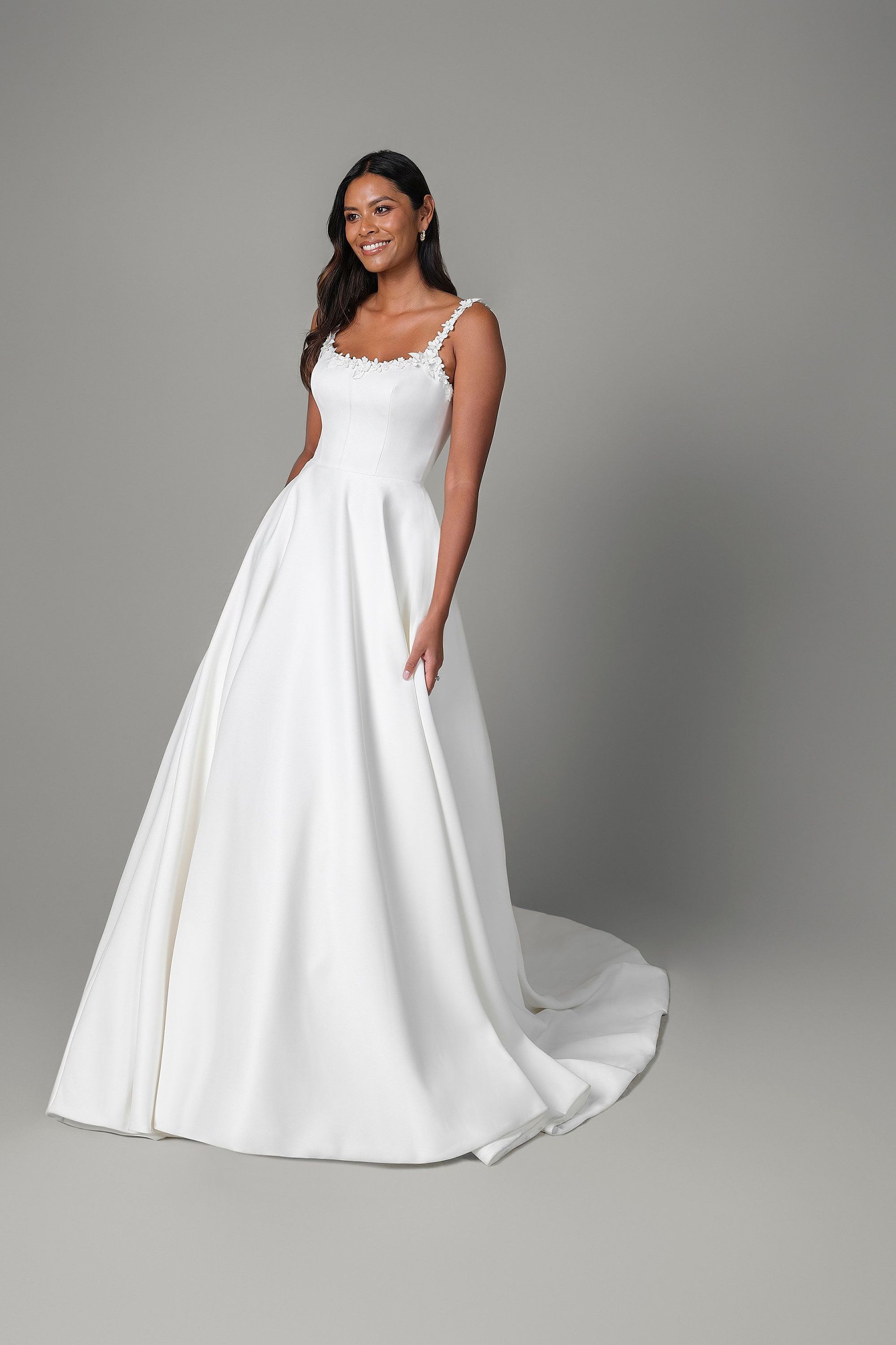 A woman in a white wedding dress is standing on a white background.