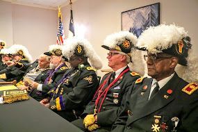 Uniformed officials in feathered hats seated at a conference table in a meeting room