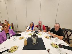 People seated around a banquet table with food and a lantern centerpiece in a conference room