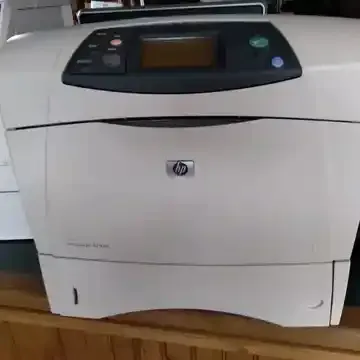 A white hp printer is sitting on top of a wooden table.