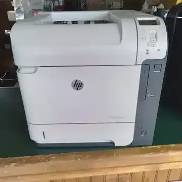 A white hp printer is sitting on top of a wooden table.