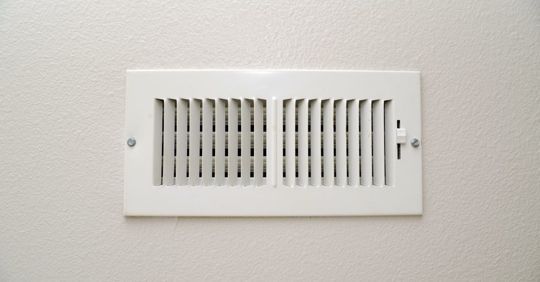 White rectangular air vent on a white wall, with vertical slats. White rectangular air vent on a white wall, with vertical slats.