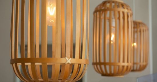Three bamboo pendant lights with visible light bulbs, hanging indoors. Three bamboo pendant lights with visible light bulbs, hanging indoors.
