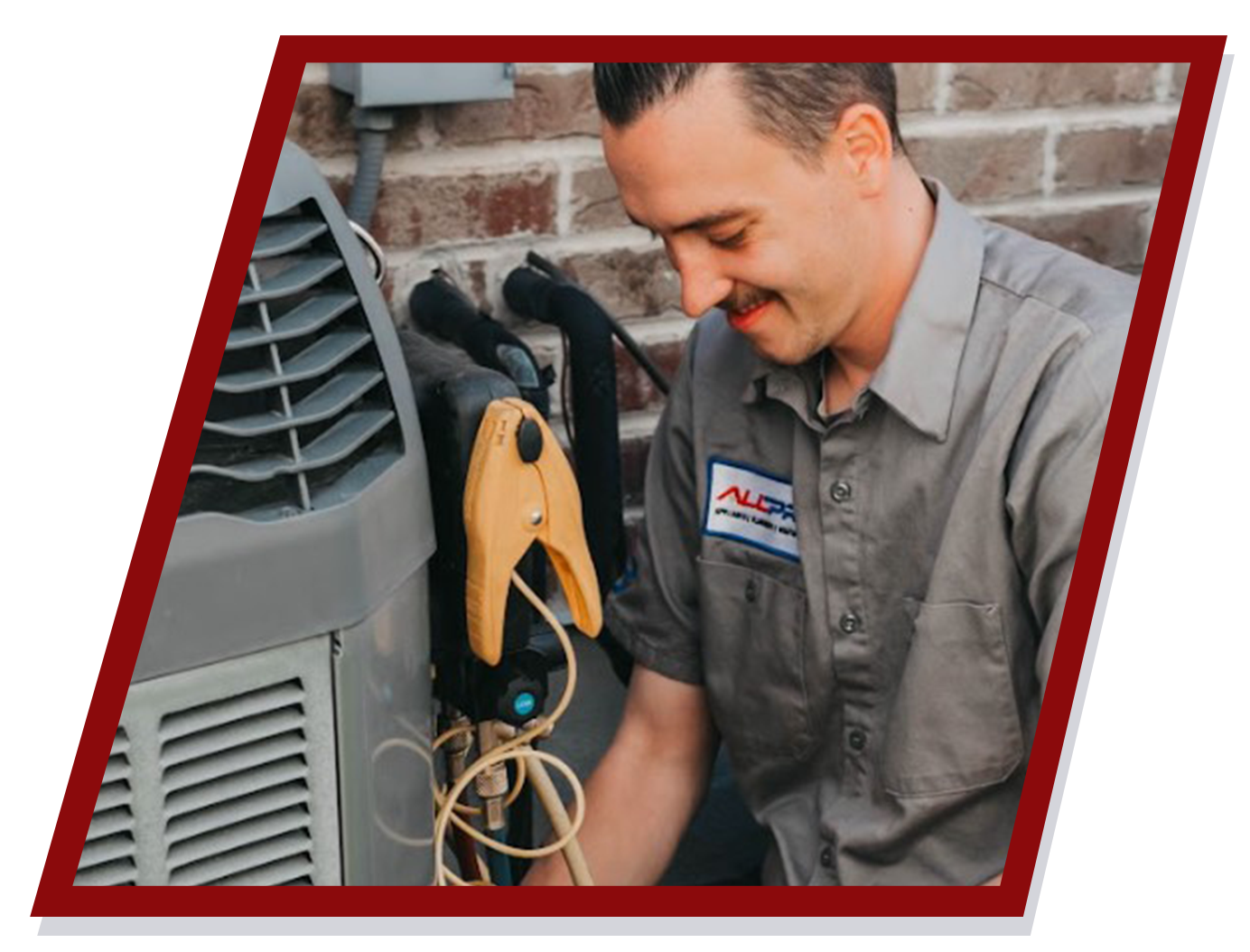 HVAC technician smiling while working on an air conditioning unit outside a brick building. HVAC technician smiling while working on an air conditioning unit outside a brick building.