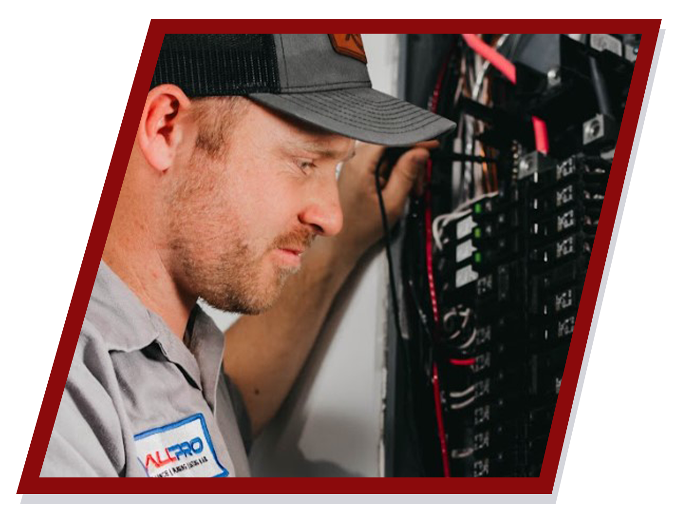 Electrician examining a circuit breaker panel, wearing a cap and work shirt.