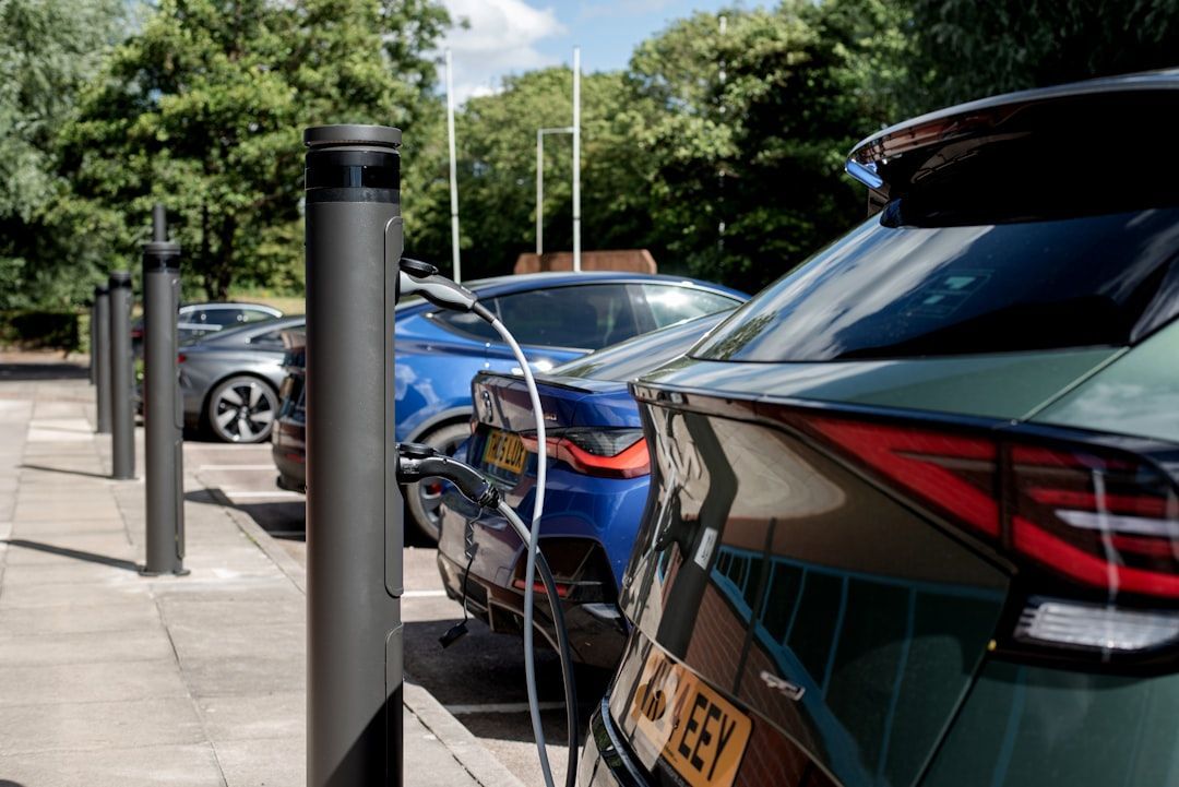 Modern electric vehicles plugged into commercial charging stations outside an office building
