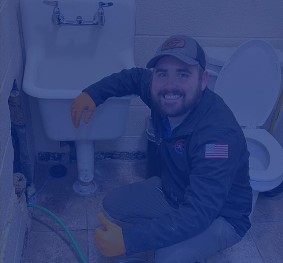 Plumber kneels near sink and toilet, giving a thumbs-up. Wearing cap and work clothes, smiling. Plumber kneels near sink and toilet, giving a thumbs-up. Wearing cap and work clothes, smiling.