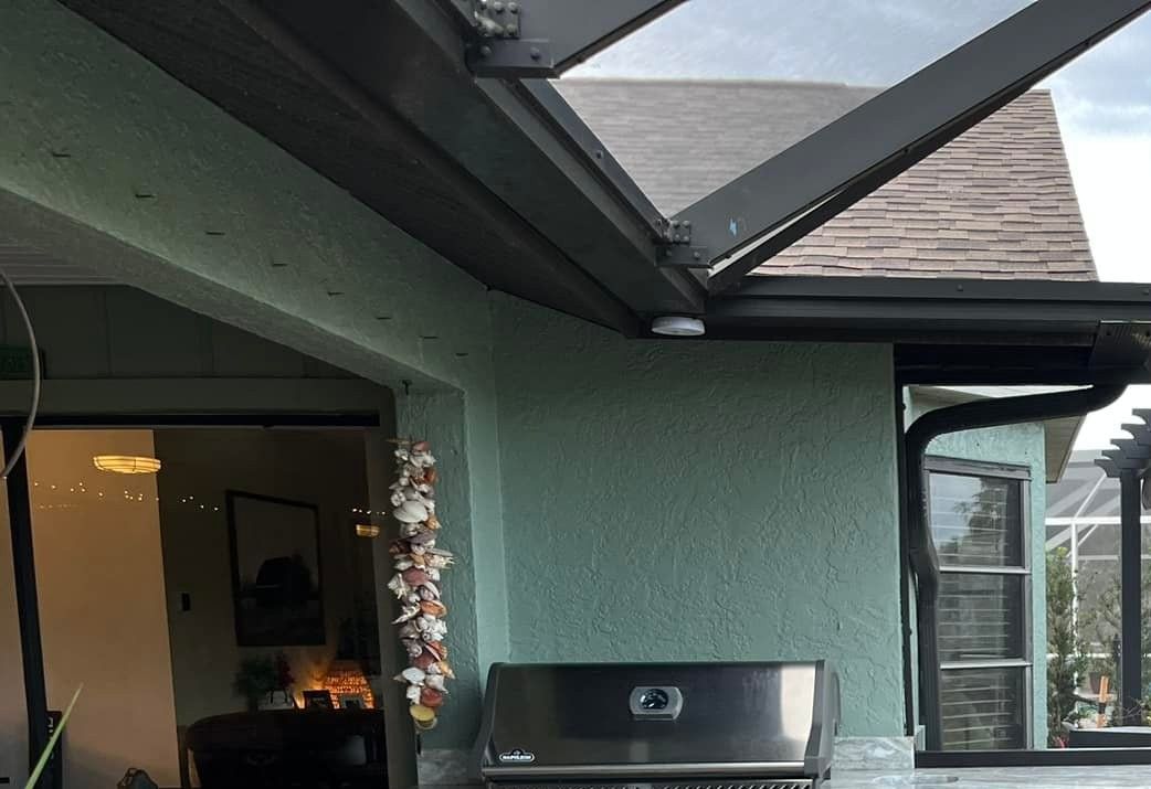 Green stucco wall with a grill below a dark gutter and a glass roof.