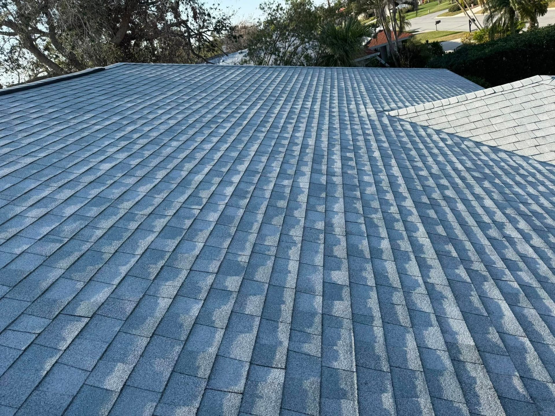 Overhead view of a gray shingle roof on a sunny day.