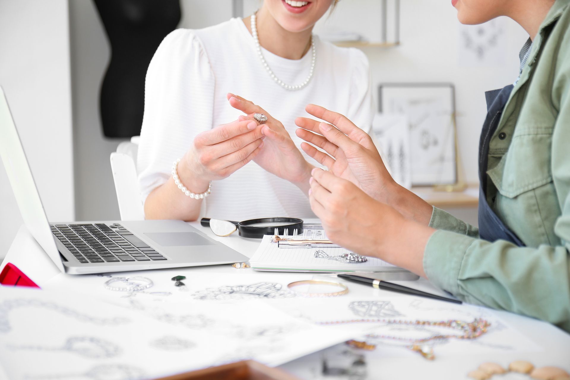 A jeweler and a client are checking sketches and adornments, showcasing a custom jewelry design.
