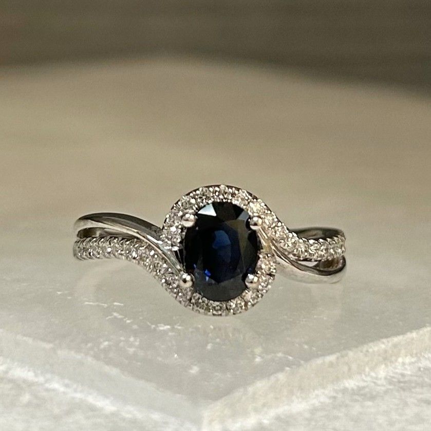 Silver ring with a dark oval gemstone surrounded by small clear stones