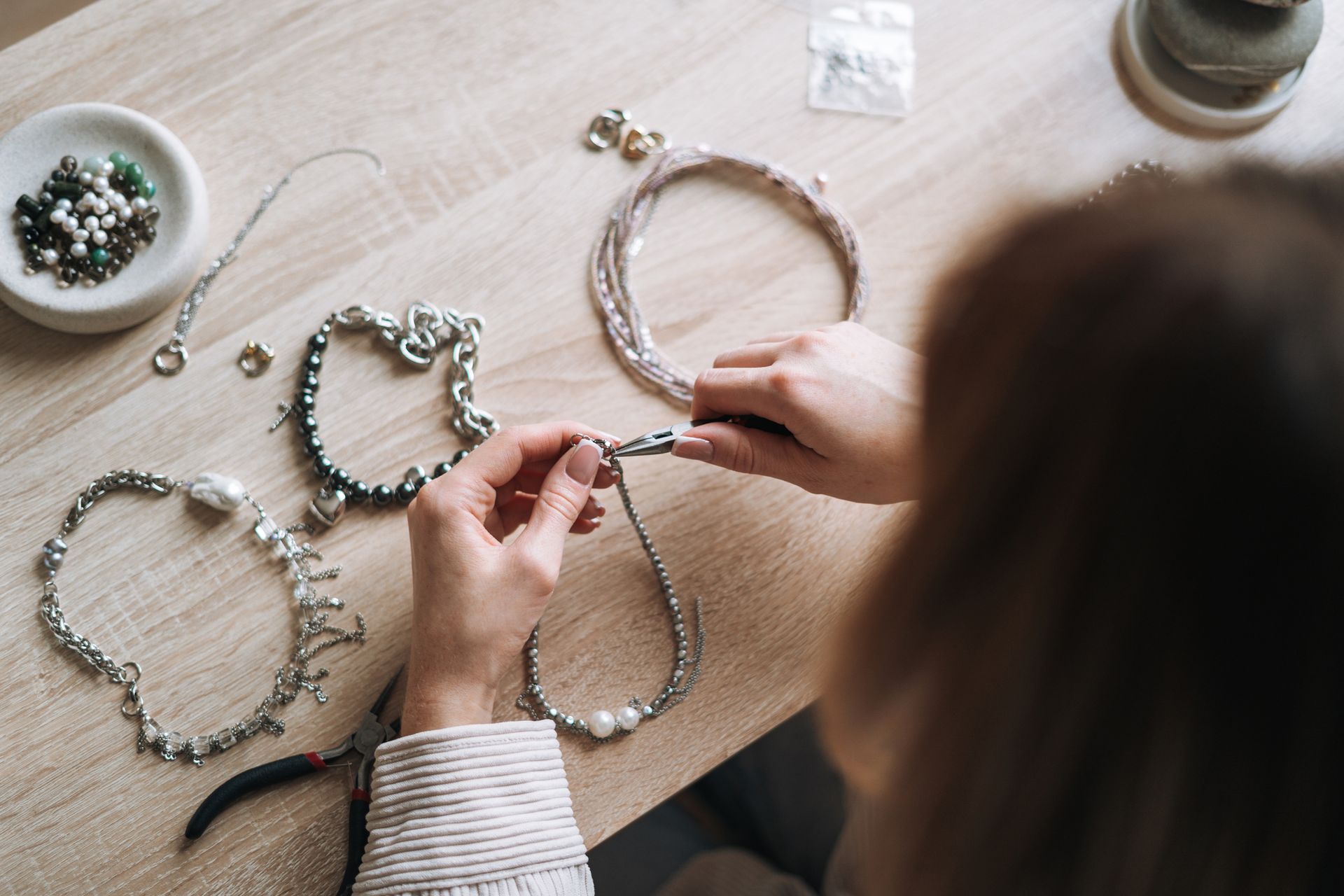 Young woman Jewelry designer creating necklace and working at table in the studio