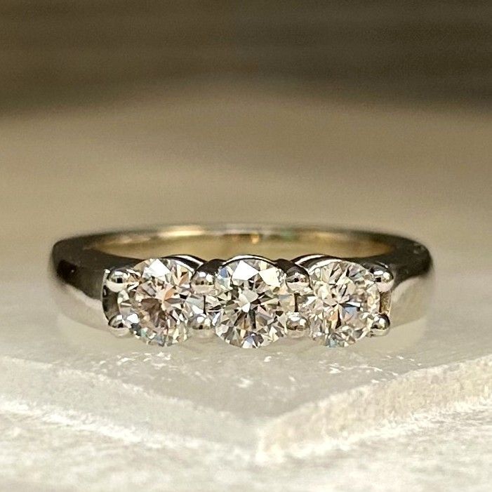 Silver ring with three clear diamonds on a white surface