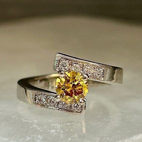 Gold ring with a yellow gemstone and small diamonds on a soft white surface