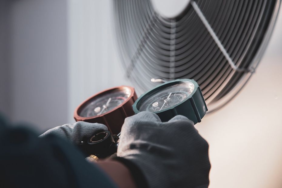 HVAC Preventative Maintenance in Holly Springs, NC Gloved hands holding two round car lights near a large fan or vent