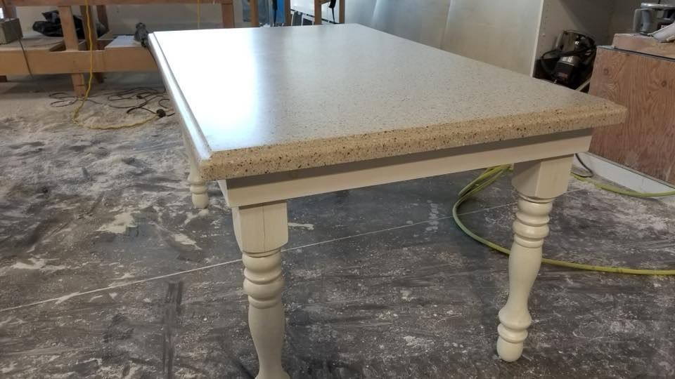 Light-colored speckled countertop table with off-white, turned legs in a workshop setting.