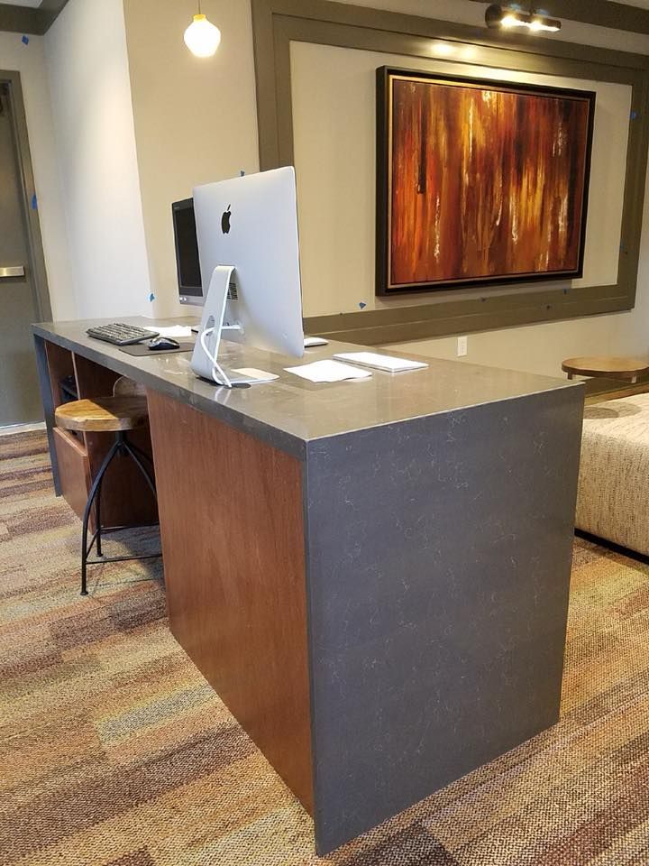 Office desk with computer, chair, and artwork in a lobby setting.
