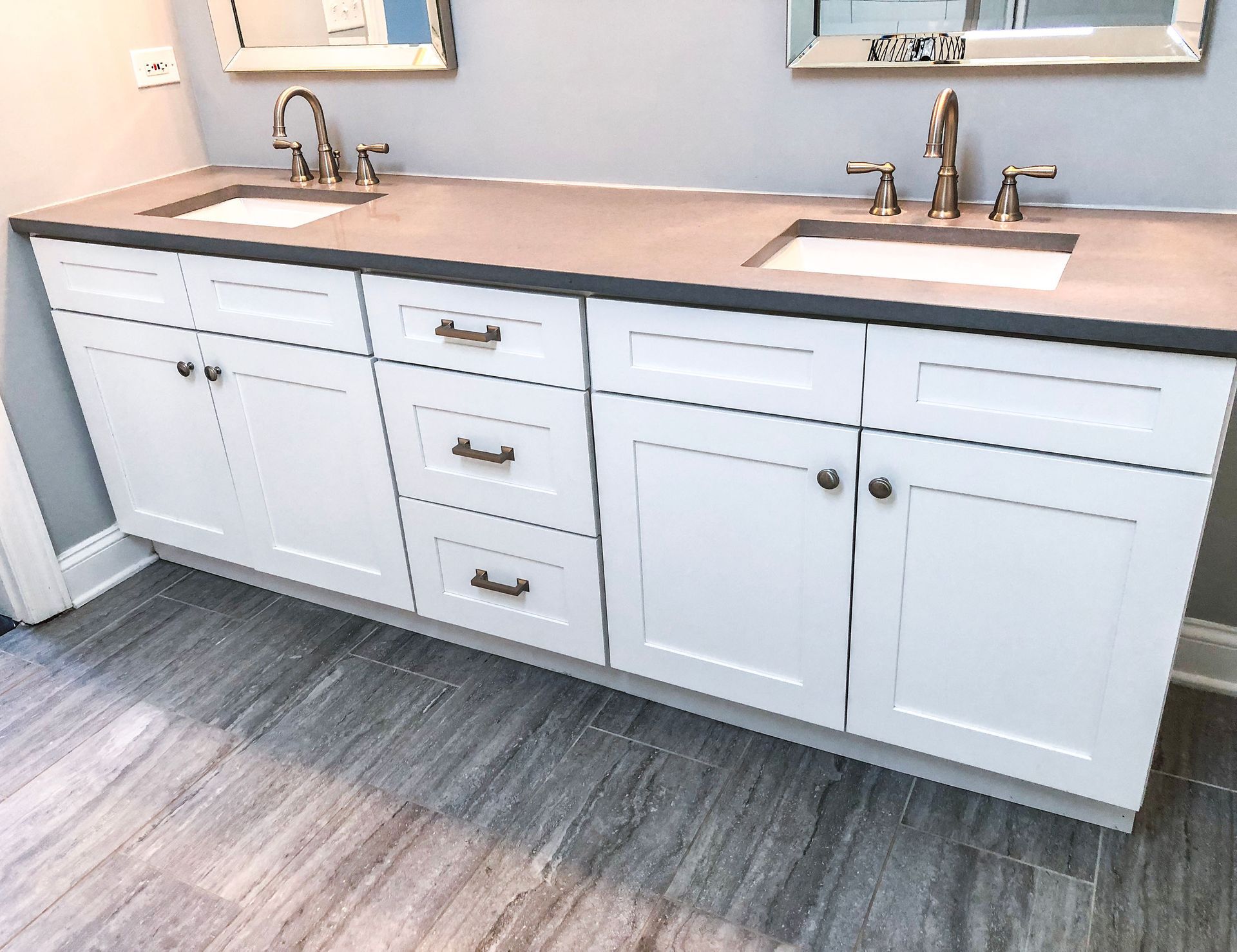 White double vanity with gray countertop and brushed nickel hardware, set on gray tiled floor.