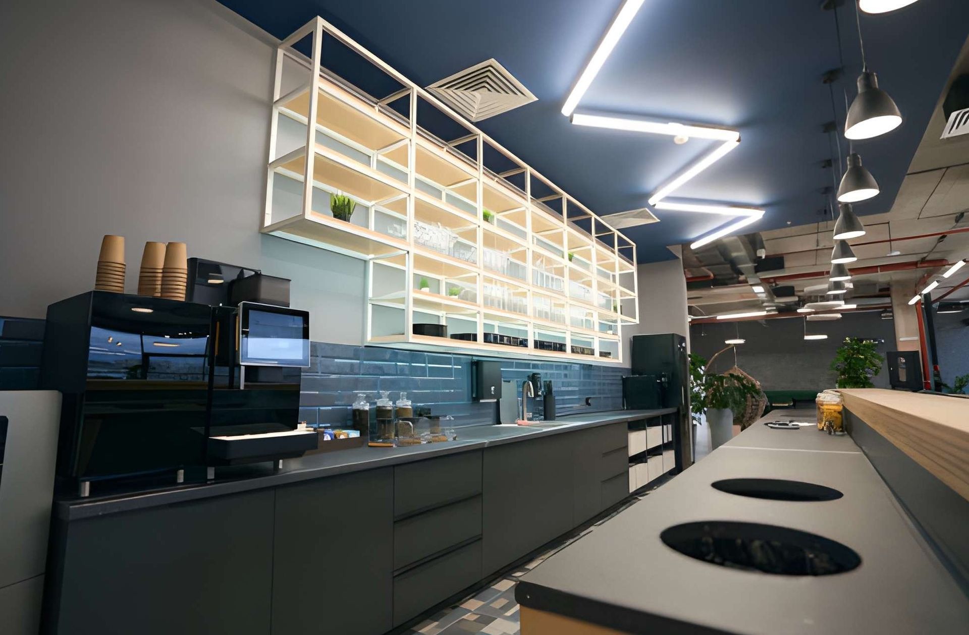 Modern office kitchen with coffee machine, wooden shelves, and gray counters.