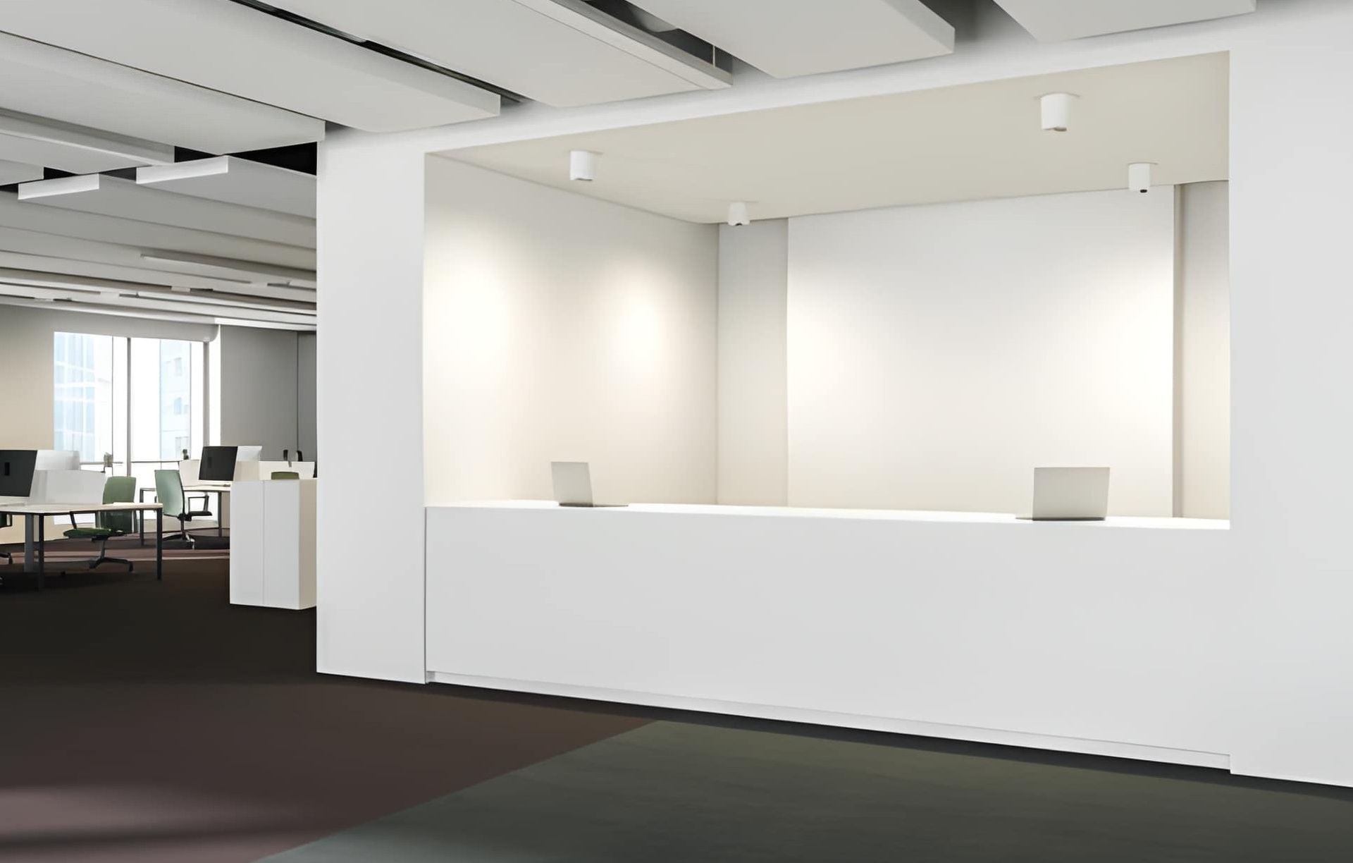 Modern white office reception desk with two laptops, an open work area in the background.