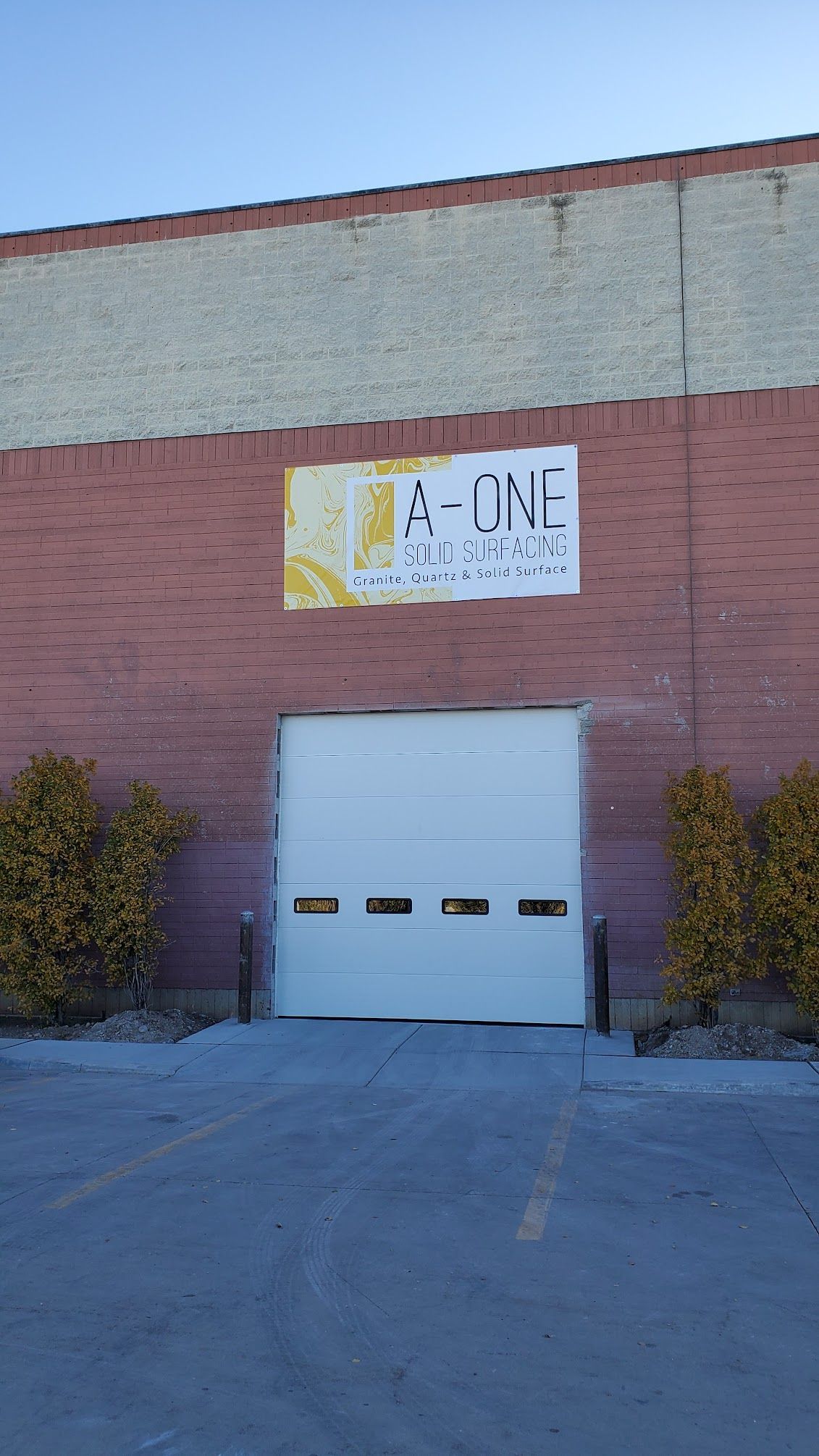 Brick building with white garage door and yellow sign, 